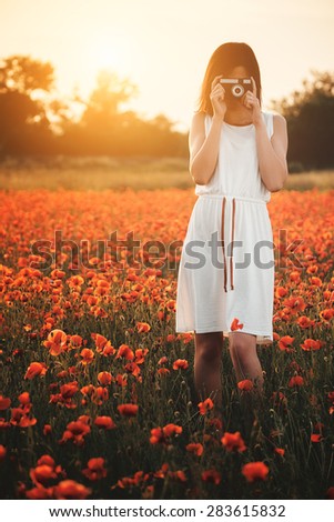 Girl taking picture on poppy field