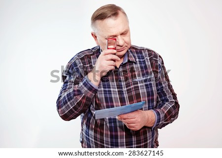 Senior man in plaid shirt reading letter with magnifying glass over white background Royalty-Free Stock Photo #283627145