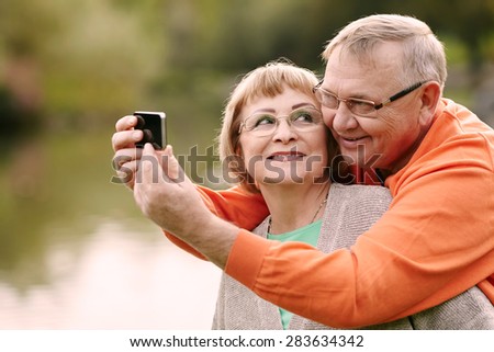 Happy smiling senior couple taking picture of themselves with smartphone outdoor