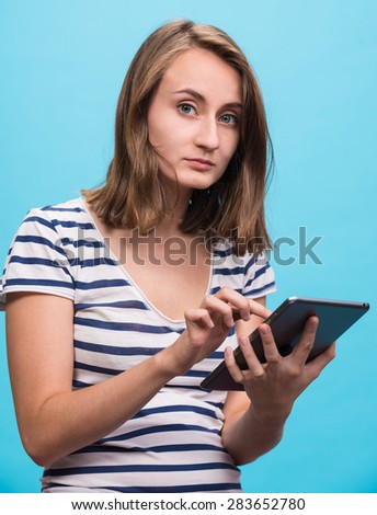 Serious girl with tablet pc computer on blue background