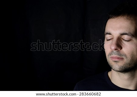 young man with closed eyes, black background Royalty-Free Stock Photo #283660682