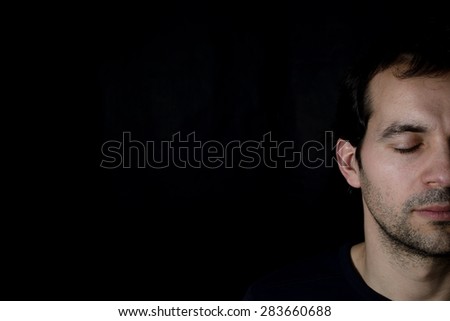 young man with closed eyes, black background Royalty-Free Stock Photo #283660688