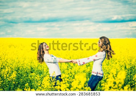 Two pretty girls in the yellow field in embroidery shirts
