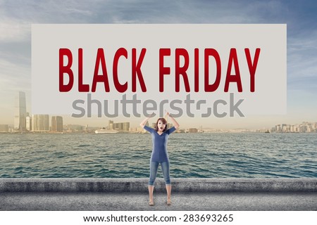 Black Friday, words on blank board hold by a young girl in the outdoor.