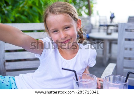 Little girls taking selfie and drinking tasty cocktails at outdoor cafe