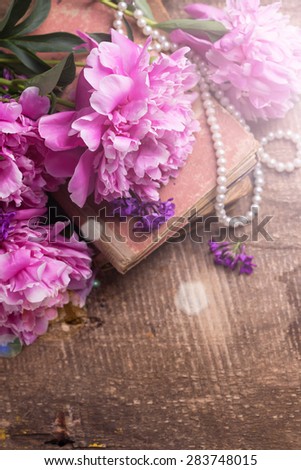 Vintage background. Splendid  pink  peonies flowers  in ray of light on aged wooden background. Selective focus. Place for text.

