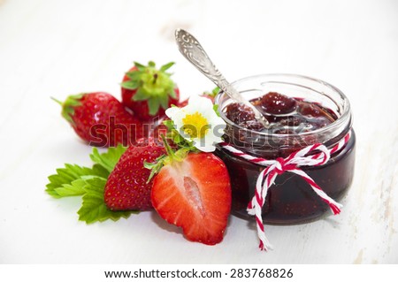 Fresh strawberry jam in a jar of strawberries on a wooden background