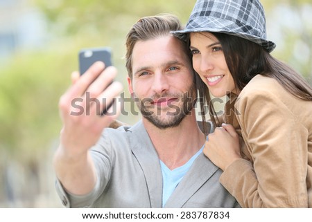 Cheerful young couple taking selfie picture with smartphone