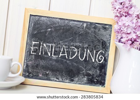 flower in white vase greeting card background with blackboard german for invitation