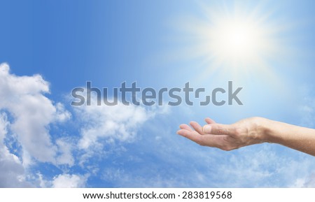 Sensing Solar Energy - Female hand out stretched facing upwards, sensing Solar Energy on a blue sky background, with bright sunburst above and plenty of copy space