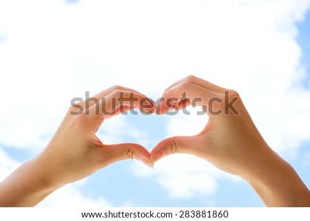 Woman hands making heart shape with background of blue sky