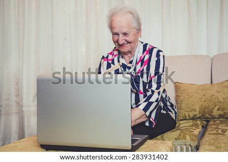 Senior woman smiling and using laptop