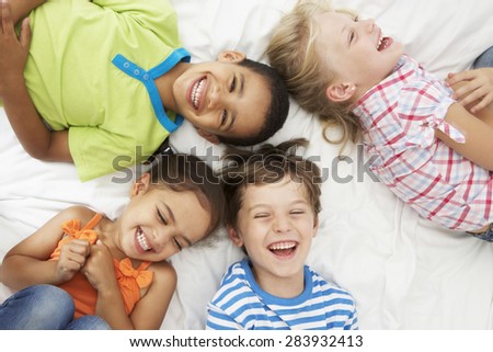 Overhead View Of Four Children Playing On Bed Together Royalty-Free Stock Photo #283932413