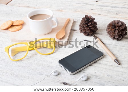 Smart phone and coffee cup,eyeglasses on wooden table.