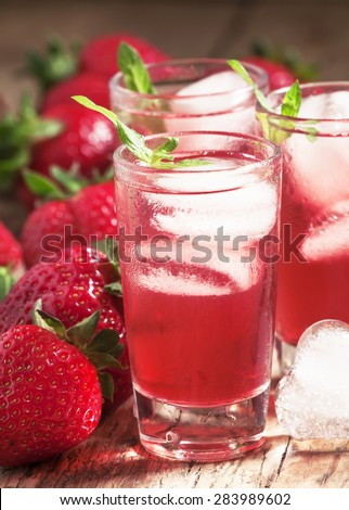 Fresh strawberry juice with ice in the shape of hearts and berries on a wooden table, selective focus