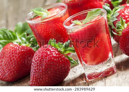 Fresh strawberry juice with strawberry slices on a wooden table, selective focus