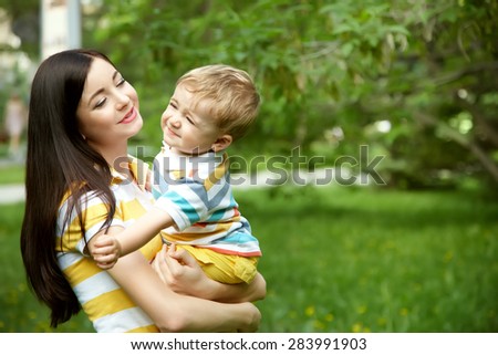 outdoor portrait of mother and son on green background. child and mom walk in the summer park
