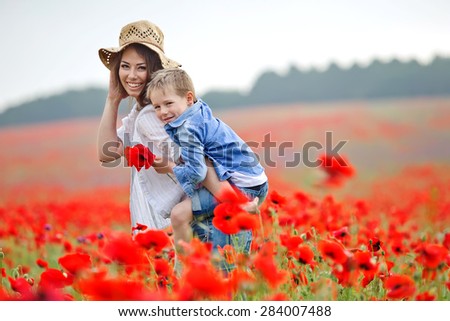 Mother playing with her toddler child in poppy field