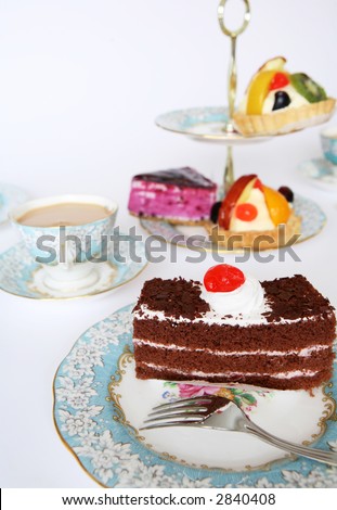 A slice of chocolate cake tempting the palate at teatime. Other cakes are offered on the traditional cake-stand. Royalty-Free Stock Photo #2840408