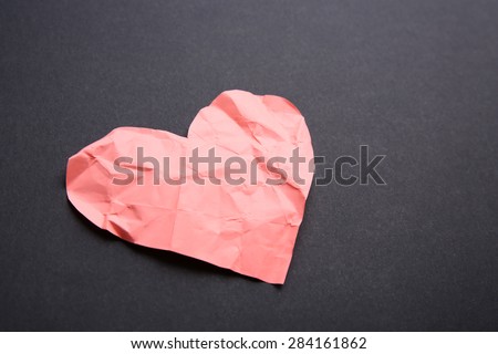 Crumpled paper heart on black background