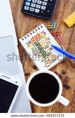 Stock Analysis word cloud arrangement concept on note nook. Notebook,smartphone, calculator and a cup of coffee on wooden table.