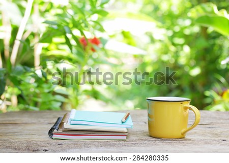 Notebook  and coffee in yellow cup on wooden table