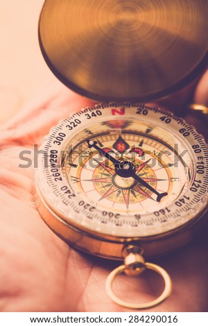 Man hand hold compass to look for direction. Vintage filter