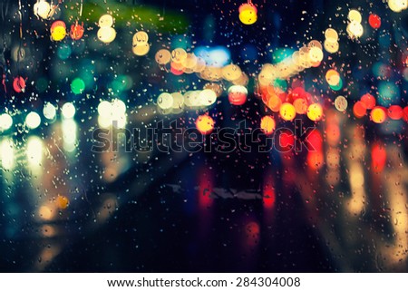 night city life through windshield: cars, lights and rain