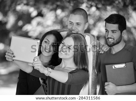 friendship, leisure, summer, technology and people concept - group of smiling friends making selfie with  tablet pc in park