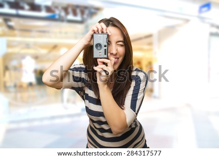 Smiling woman with retro photo camera. Over shopping center background