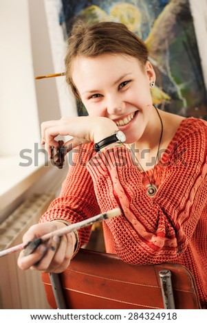 Portrait of beautiful woman artist with smile and positive emotion in home art studio