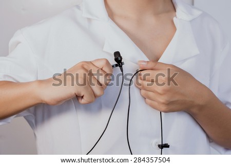 A woman clipping  tie-clip microphone