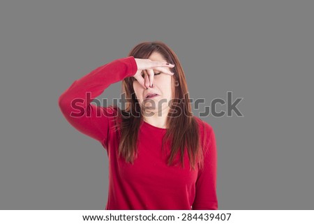 Young girl holding her nose  smelling something stinking with funny expression