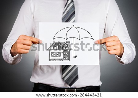 Home insurance concept. Businessman holding paper with black and white drawing of a house under the umbrella.