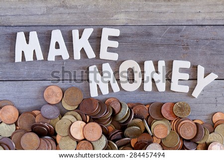 The words make money over a wooden surface and a lot of coins