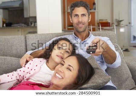 Hispanic Family Sitting On Sofa And Watching TV