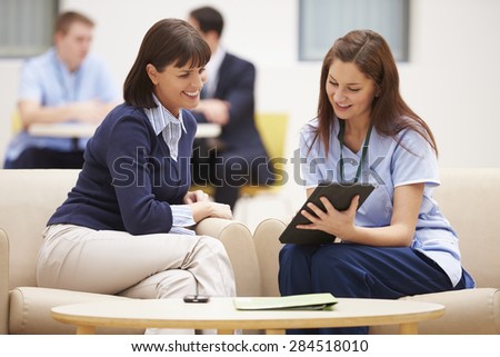 Woman Discussing Results With Nurse On Digital Tablet