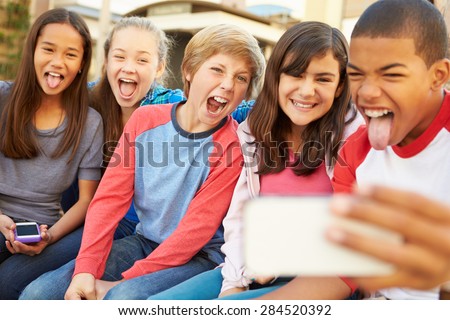 Group Of Children Sitting On Bench In Mall Taking Selfie Royalty-Free Stock Photo #284520392