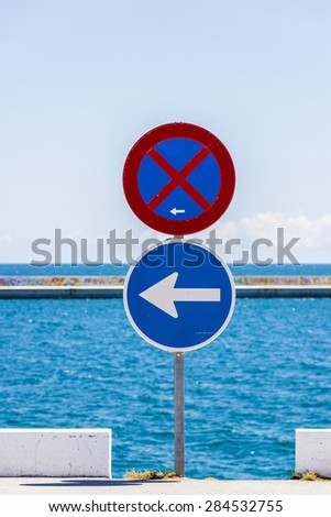 No parking sign and another sign of compulsory direction with the sea and sky background