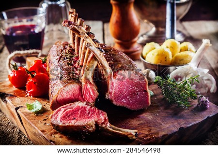 Rare Rectangle Rack of Lamb on Wooden Cutting Board Surrounded by Fresh Herbs and Ingredients Royalty-Free Stock Photo #284546498