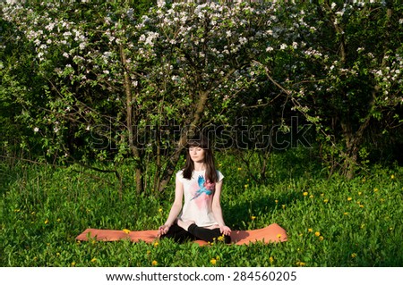 Young woman doing yoga on natural background. Spring garden