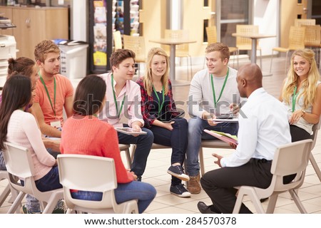 College Students With Tutor Having Discussion
