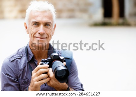 Senior man with camera in city