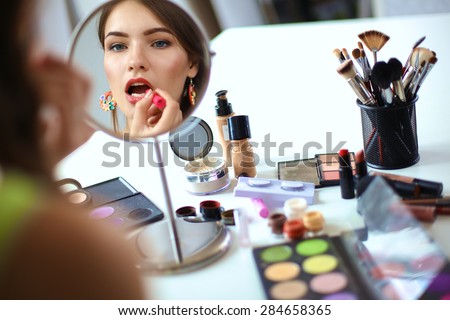 Young beautiful woman making make-up near mirror,sitting at the desk Royalty-Free Stock Photo #284658365