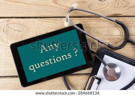 Any questions ? - Workplace of a doctor. Tablet, stethoscope, clipboard on wooden desk background. Top view