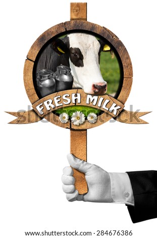Fresh Milk  / Hand of waiter holding a wooden sign with head of cow, cans of milk, green grass and daisy flowers, wooden ribbon with text Fresh milk. Isolated on white background
