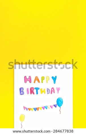 Happy birthday card with kid handwriting on yellow background, top view.