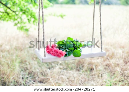 Beautiful pink flowers lying on a swing Royalty-Free Stock Photo #284728271