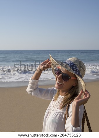 happy blonde girl smiling portrait in the beach  wearing hat and sunglasses in summer holidays