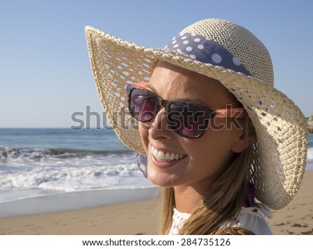 happy blonde girl smiling portrait in the beach  wearing hat and sunglasses, summer holidays